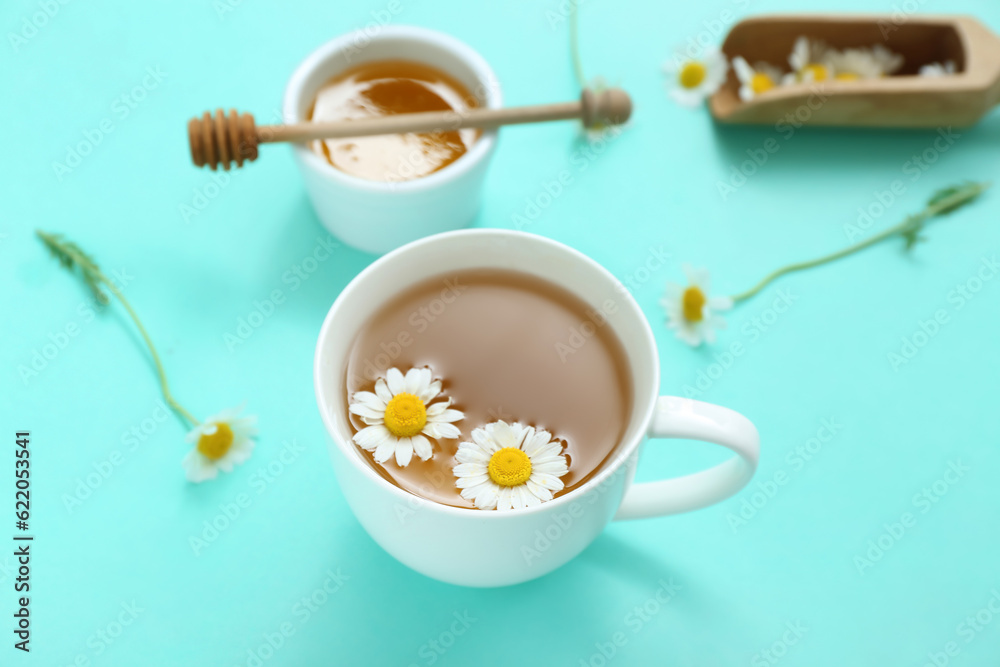 Cup of hot tea with honey and scoop on turquoise background