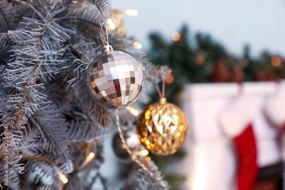 Christmas tree decorated with glowing lights, golden and silver balls in living room