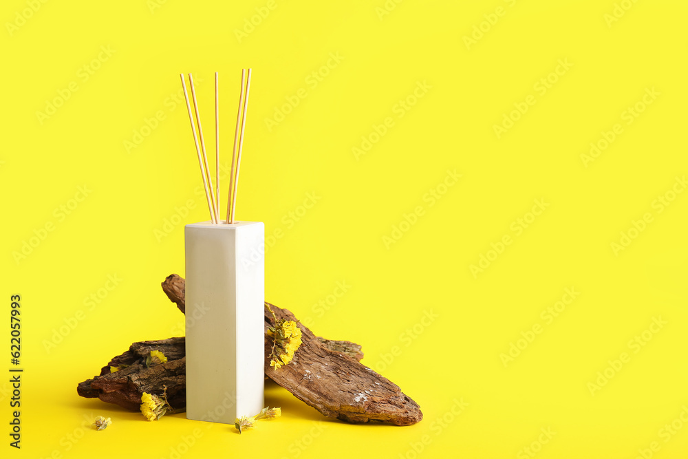 Reed diffuser and tree bark on yellow background