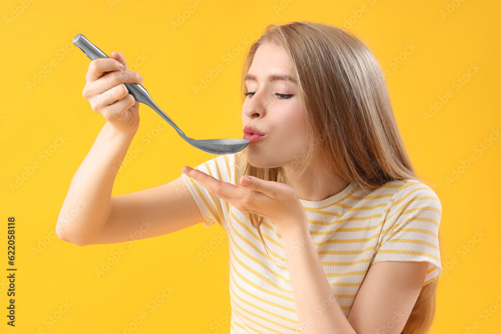 Young woman with ladle on yellow background