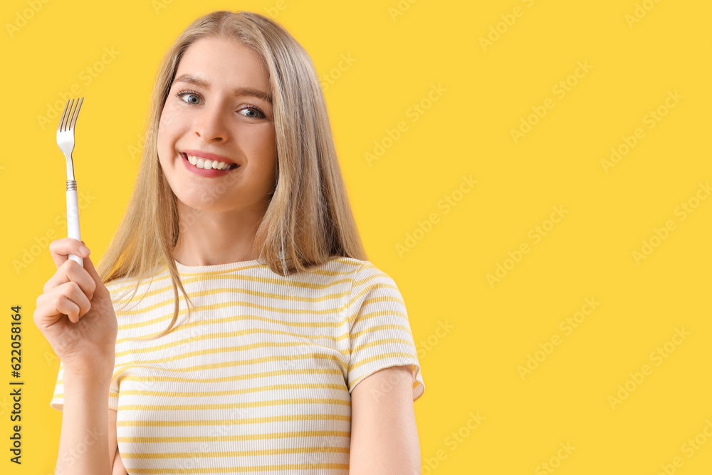 Young woman with fork on yellow background