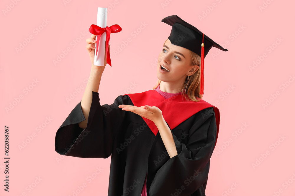 Female graduate student with diploma on pink background