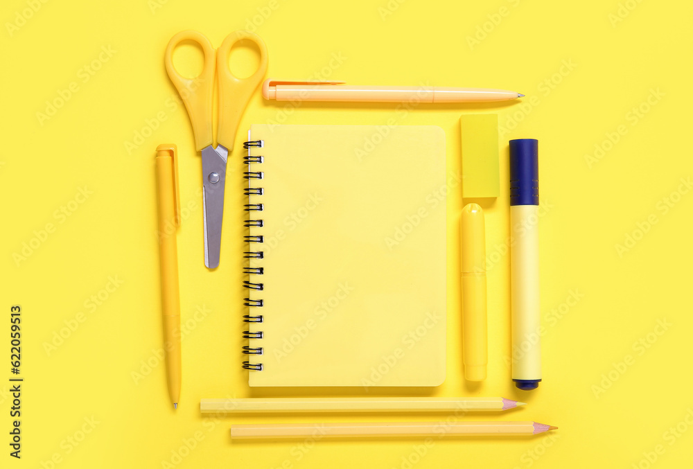 Notebook with different stationery on yellow background