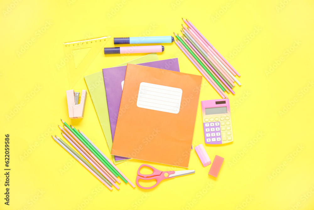 Notebooks with different stationery on yellow background