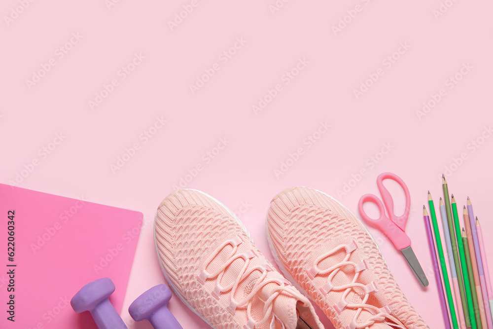 Sneakers with dumbbells and different stationery on pink background