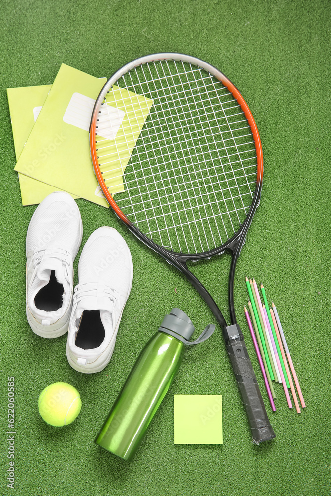 Sneakers with bottle of water, tennis ball, racket and different stationery on color background