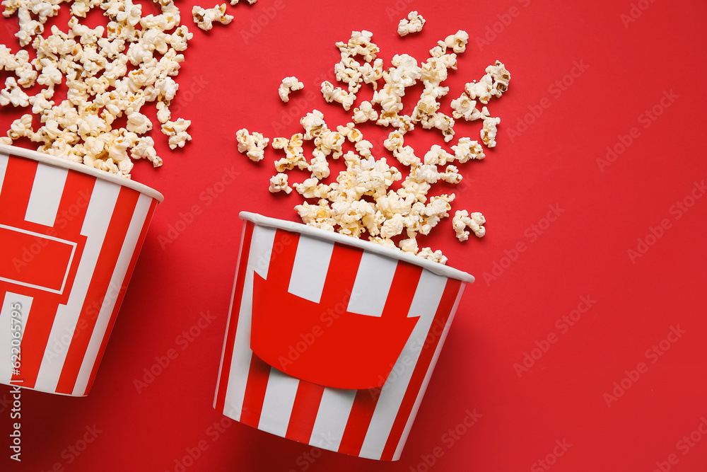 Buckets with tasty popcorn on red background