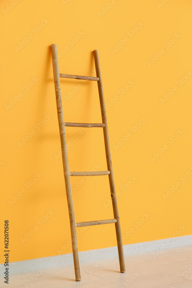 Wooden ladder near orange wall in room