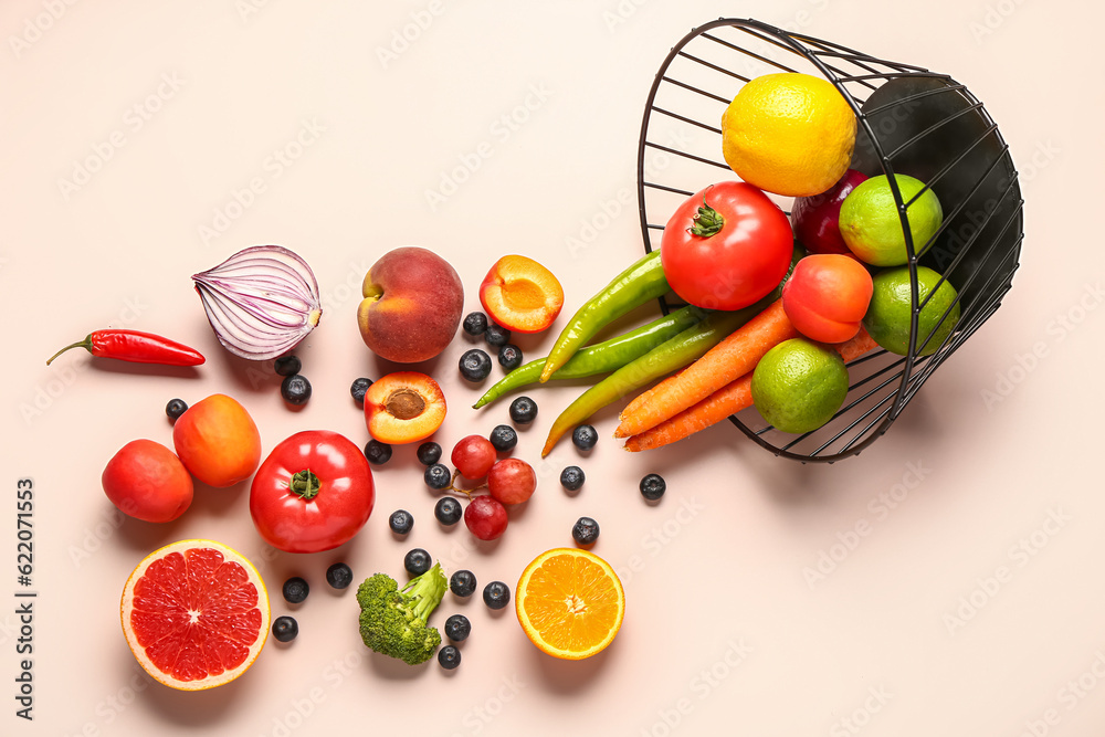 Basket with different fresh fruits and vegetables on pink background