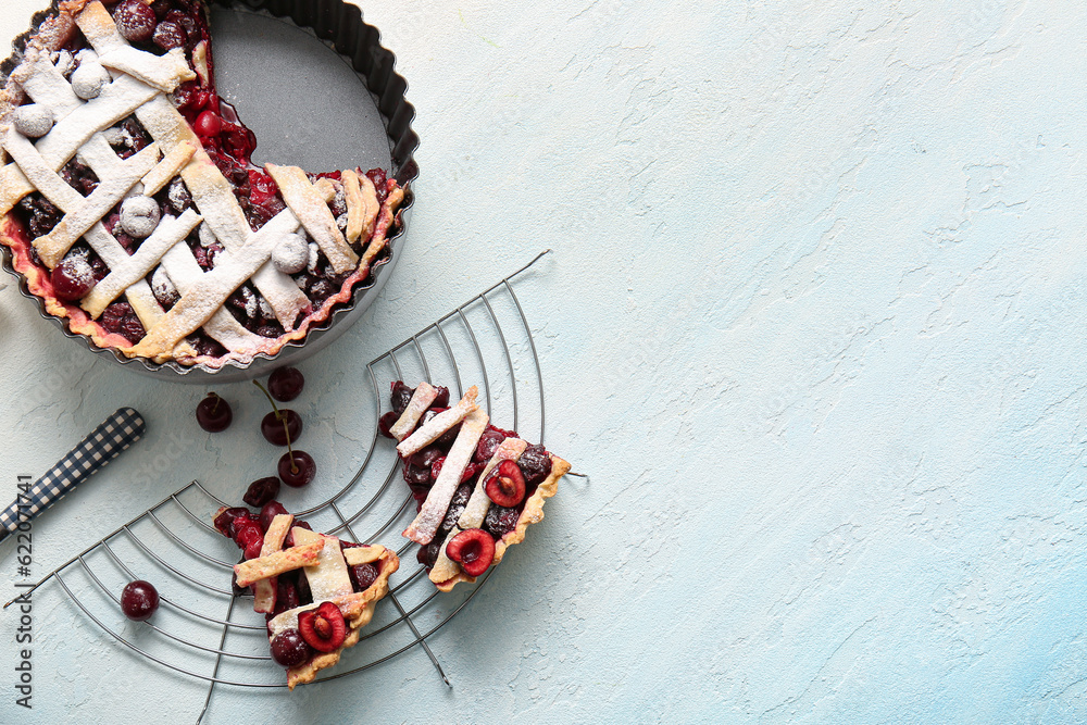 Baking dish with tasty cherry pie and stand of pieces on blue background