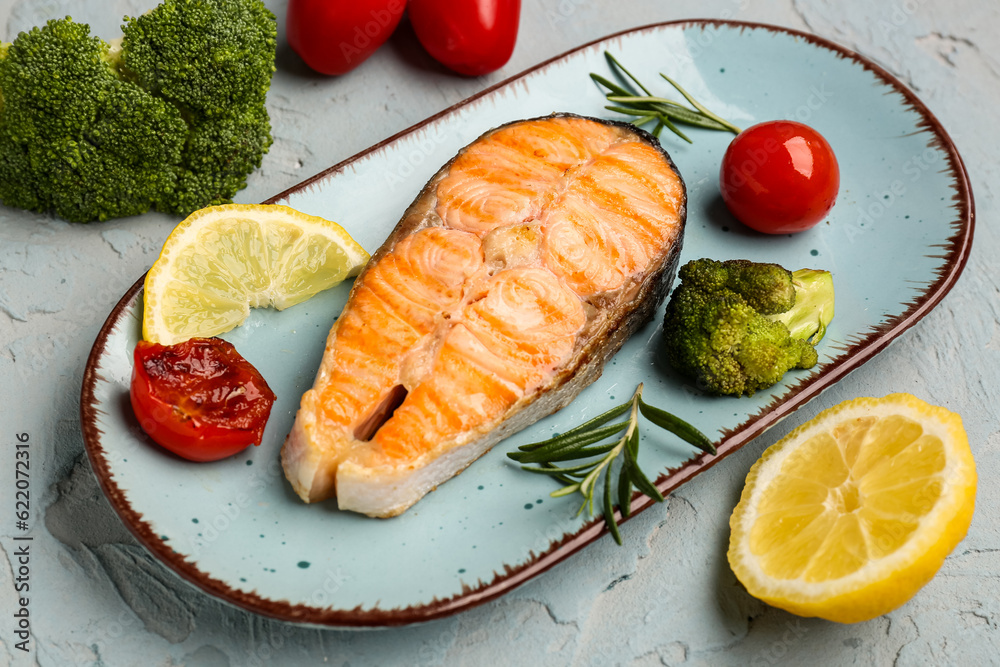 Plate with tasty grilled salmon steak on grey background