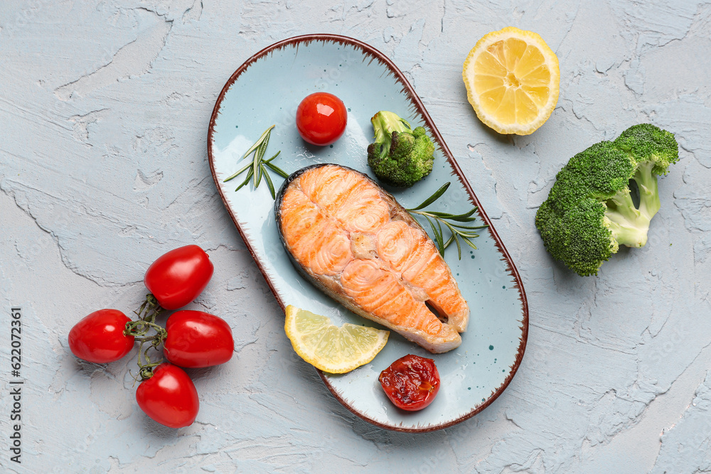 Plate with tasty grilled salmon steak on grey background