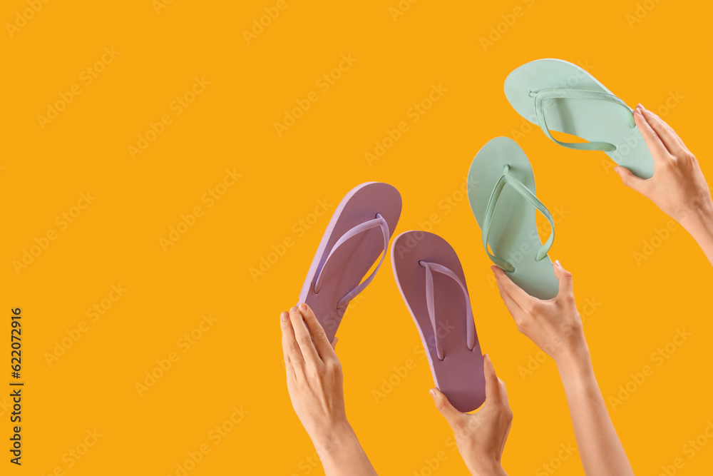 Hands with flip-flops on yellow background