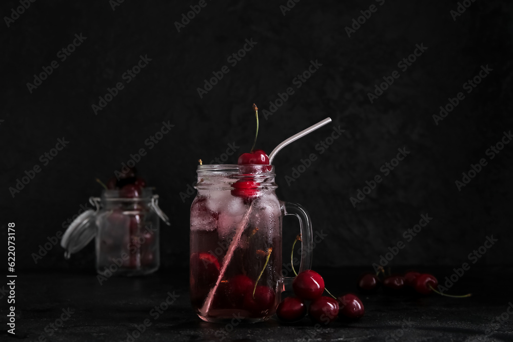 Mason jar of tasty cherry lemonade on black background