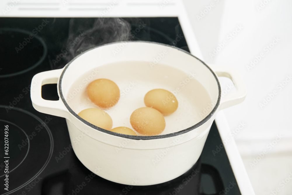 Chicken eggs boiling in cooking pot on stove