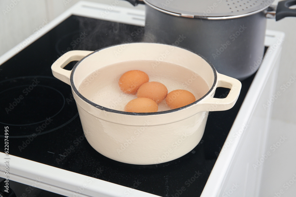 Chicken eggs boiling in cooking pot on stove