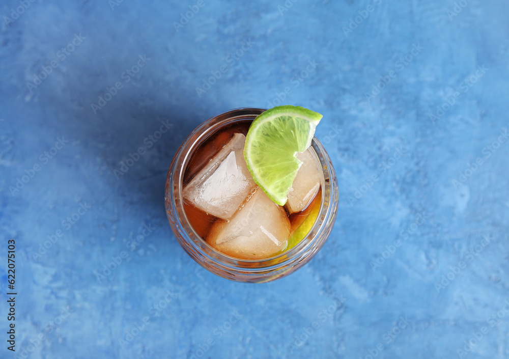 Glass of cold Cuba Libre cocktail on blue background