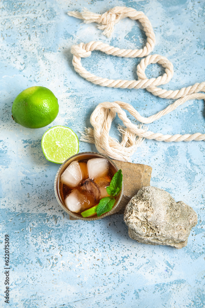 Stones with glass of cold Cuba Libre cocktail on blue background