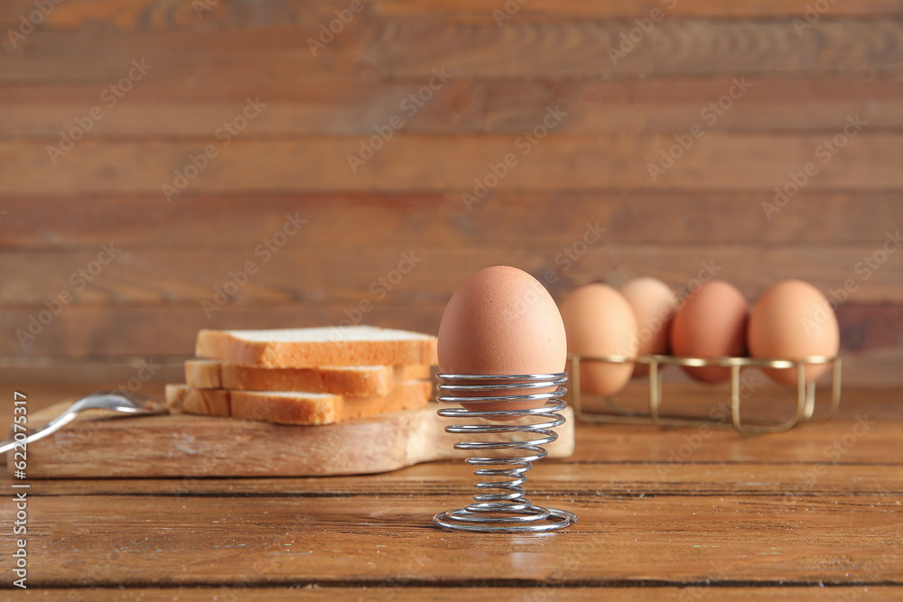 Holder with boiled chicken egg on wooden background