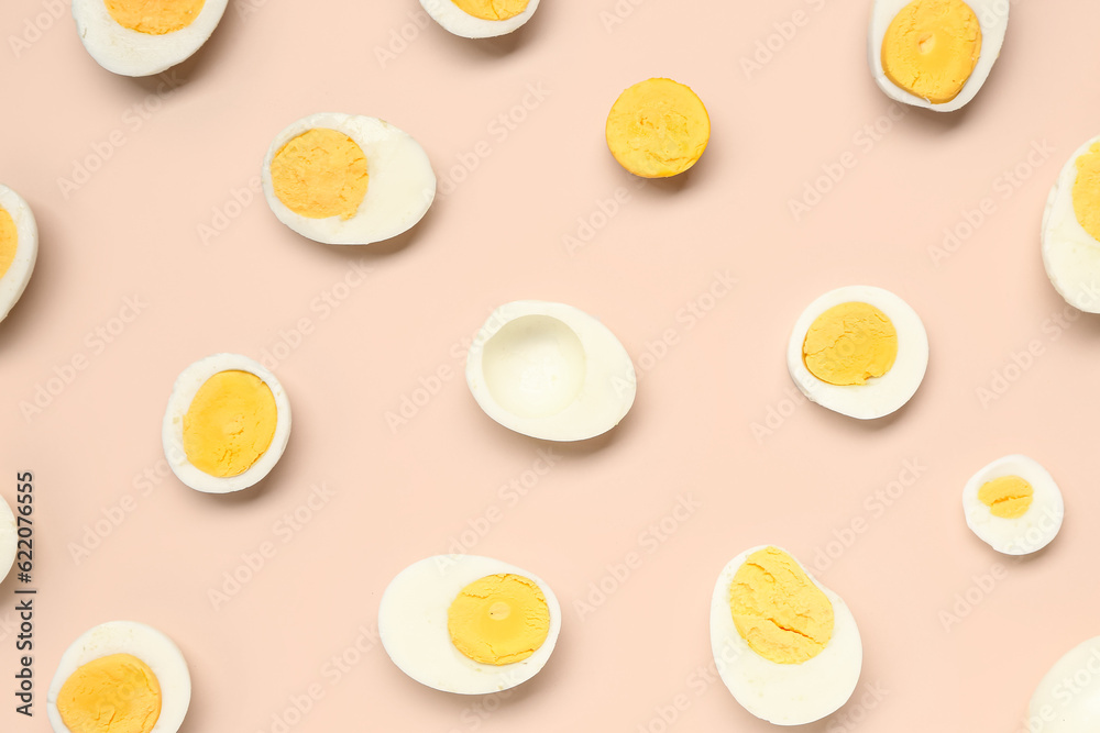 Halves of tasty boiled eggs with slices on pink background