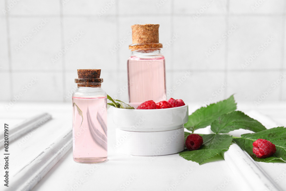 Bottles of cosmetic raspberry oil on white table