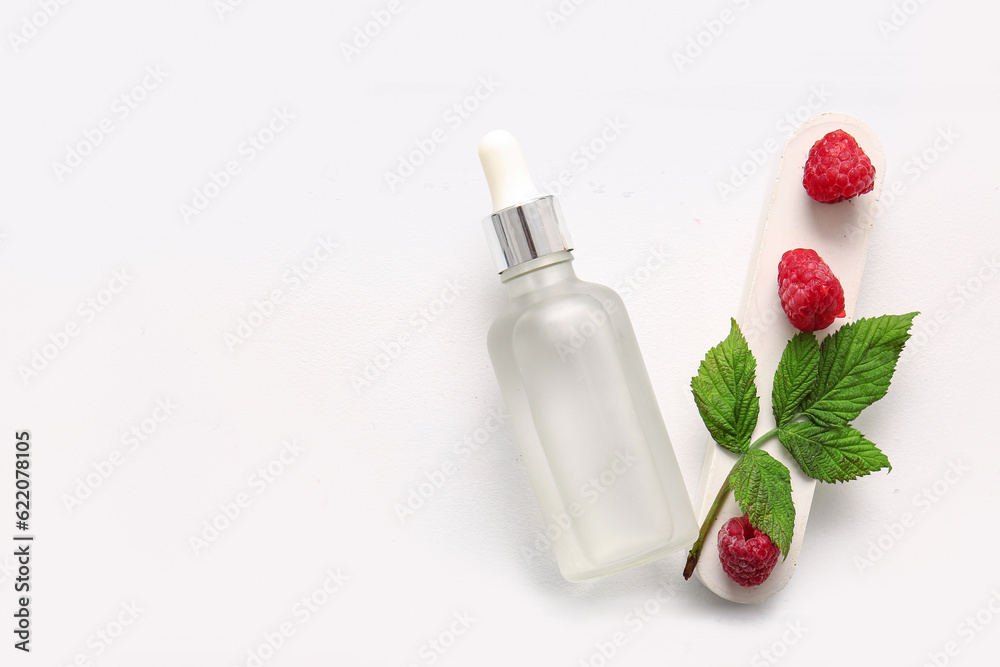 Bottle of cosmetic raspberry oil on white table