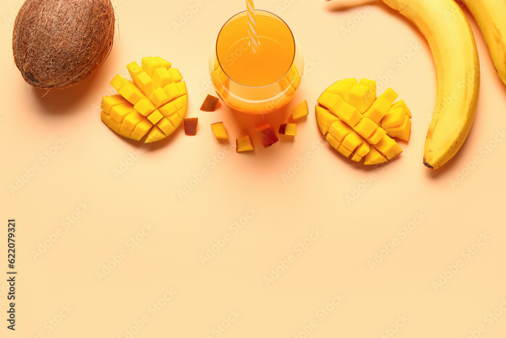 Glass of fresh mango juice with coconut and banana on orange background