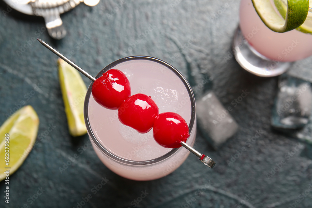 Glass of tasty cocktail with maraschino cherries on grey background