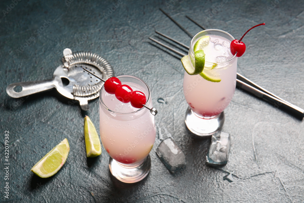 Glasses of tasty cocktail with maraschino cherries on grey background