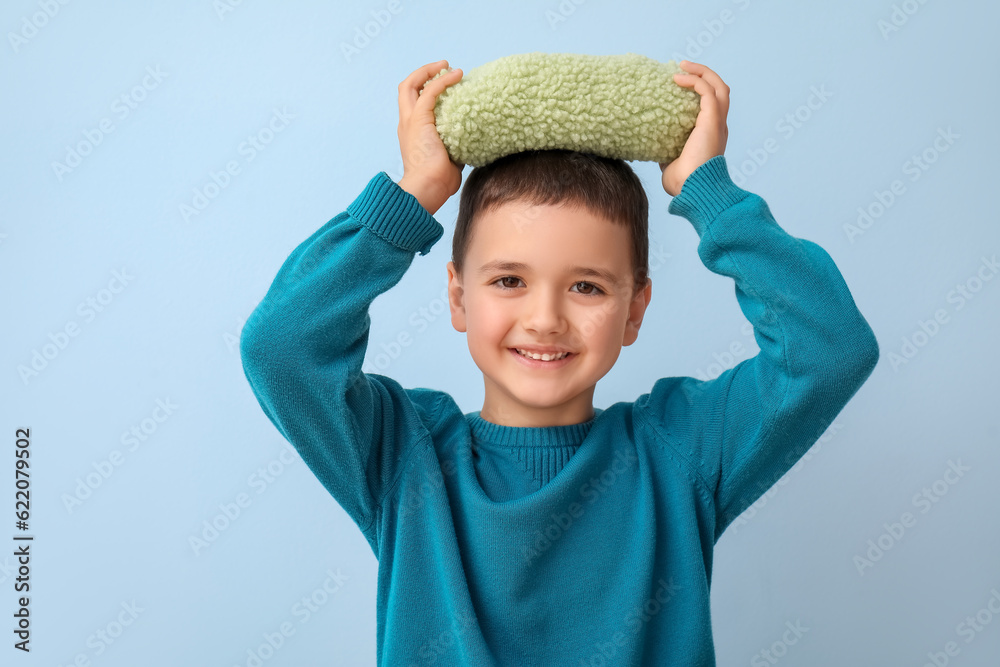 Cute little boy with pencil case on blue background