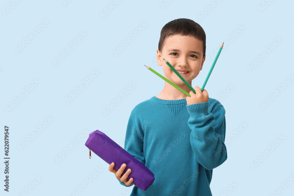 Cute little boy with pencil case on blue background