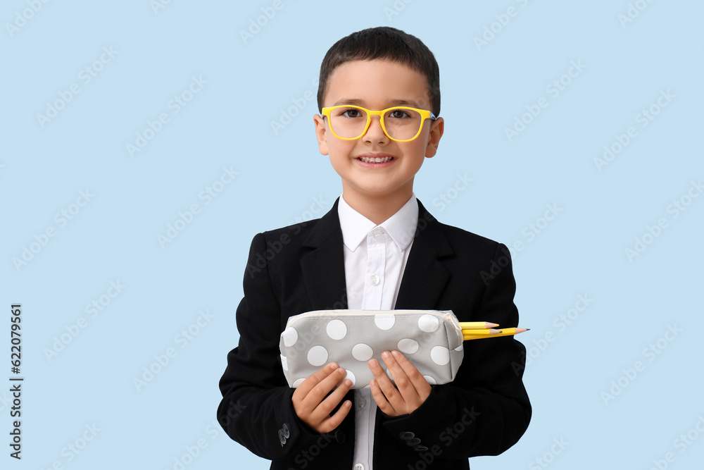 Cute little schoolboy with pencil case on blue background