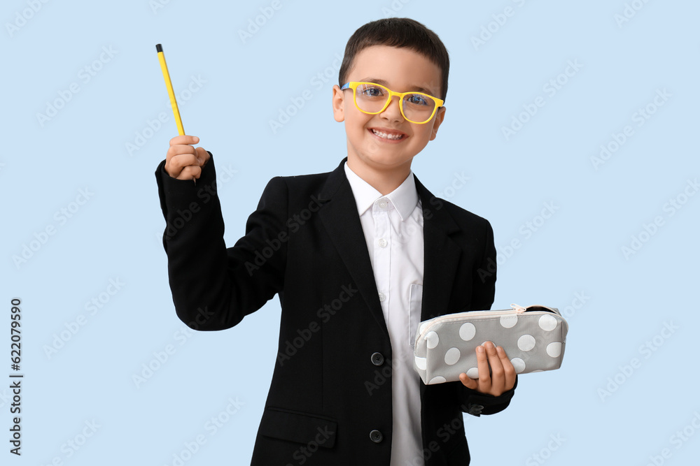 Cute little schoolboy with pencil case on blue background