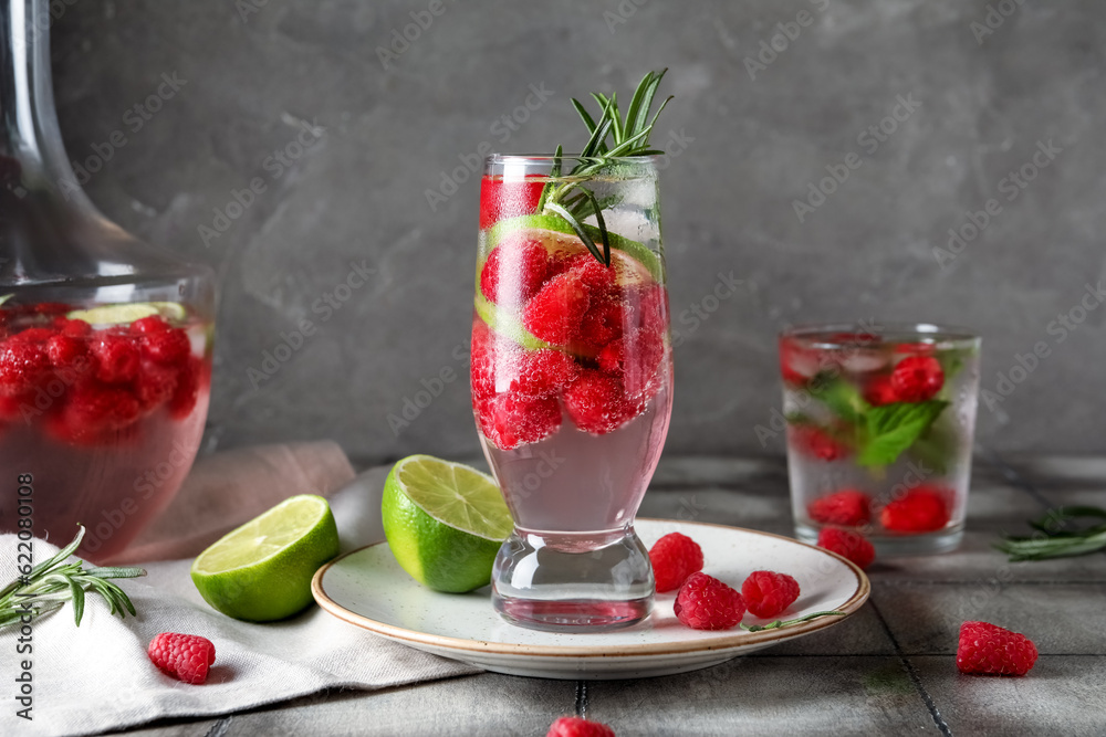 Glasses and bottle of fresh raspberry lemonade with rosemary on grey tile table