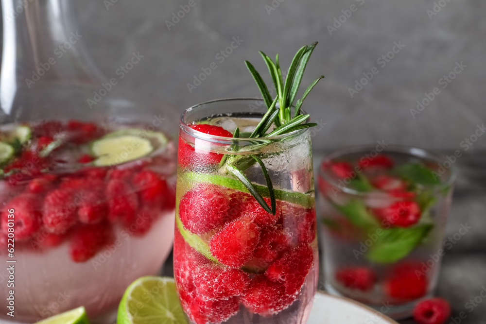 Glasses and bottle of fresh raspberry lemonade with rosemary on grey background, closeup