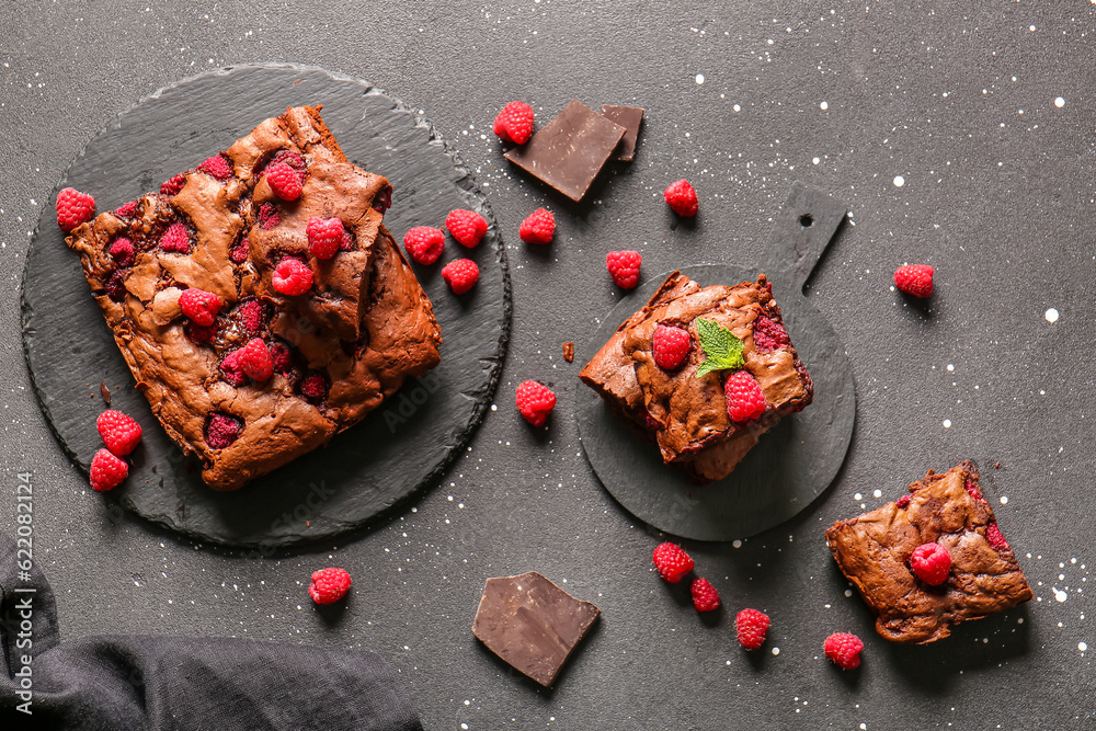 Boards with raspberry chocolate brownie and pieces on black background