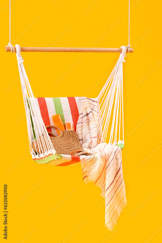 Hanging hammock with beach accessories on yellow background. Travel concept