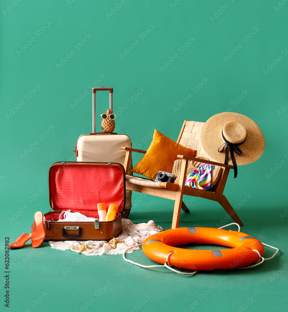 Suitcases with chair, ring buoy and beach accessories on turquoise background. Travel concept