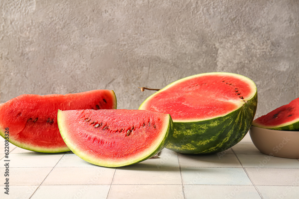 Half of fresh watermelon with pieces on white tile table