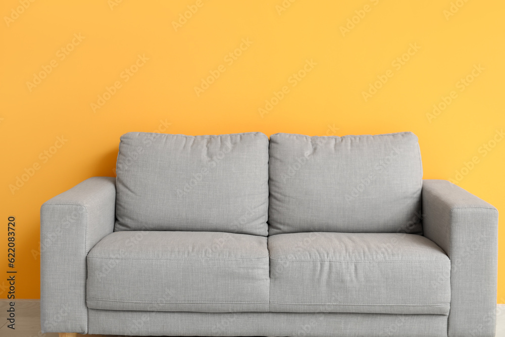 Cozy grey sofa near orange wall