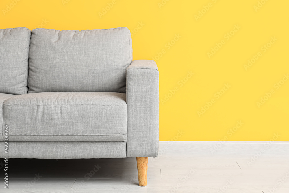 Cozy grey sofa near orange wall