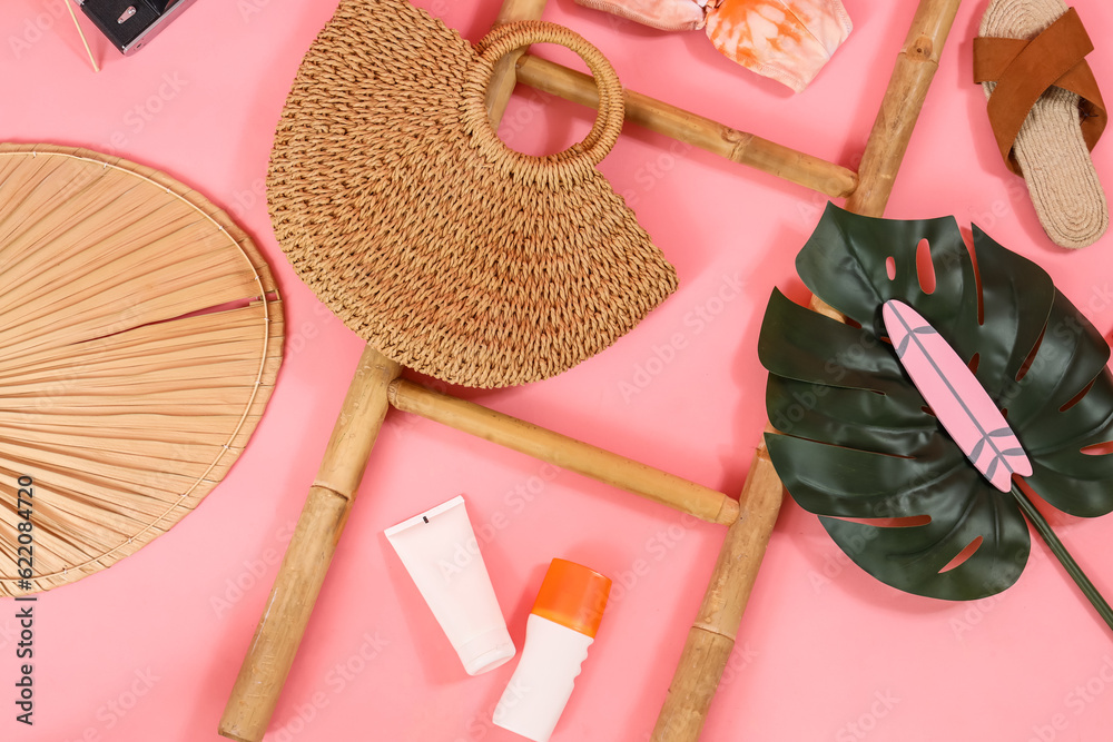 Ladder with palm leaf and beach accessories on pink background. Travel concept