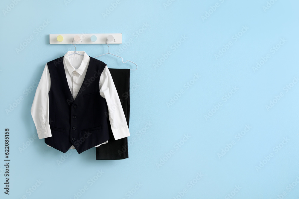 Stylish school uniform hanging on blue wall in room