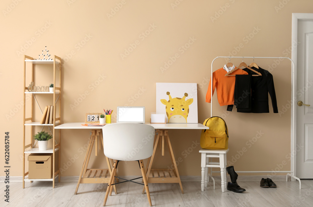 Stylish interior of childrens room with modern laptop and school uniform