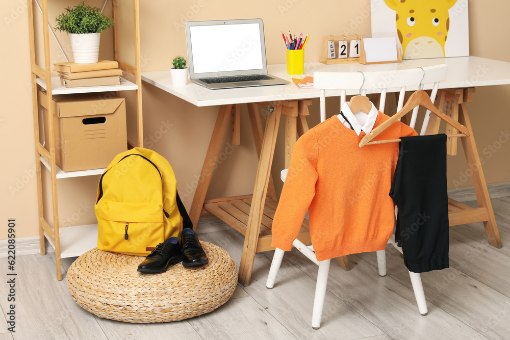 Stylish interior of childrens room with modern laptop and school uniform