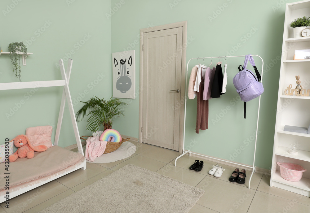 Stylish interior of childrens bedroom with school uniform and backpack