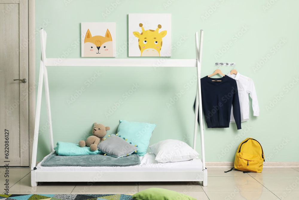 Stylish interior of childrens room with comfortable bed and school uniform