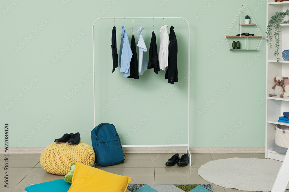 Rack with stylish school uniform and backpack in childrens room