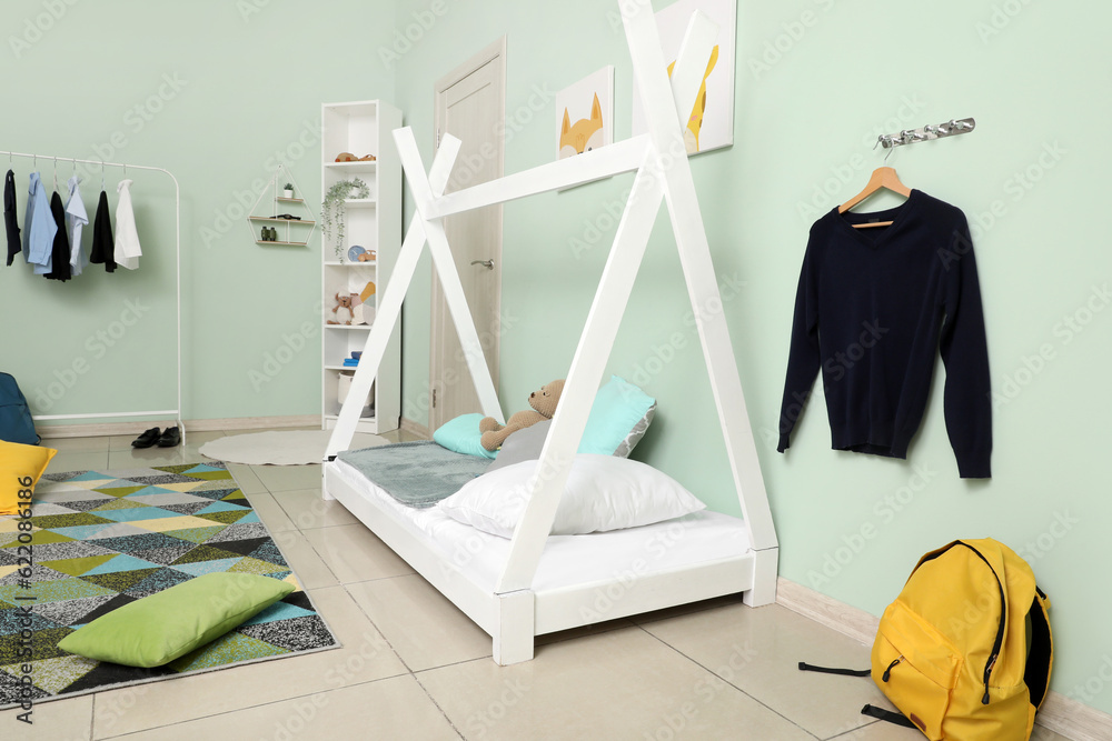 Stylish interior of childrens room with comfortable bed and school uniform