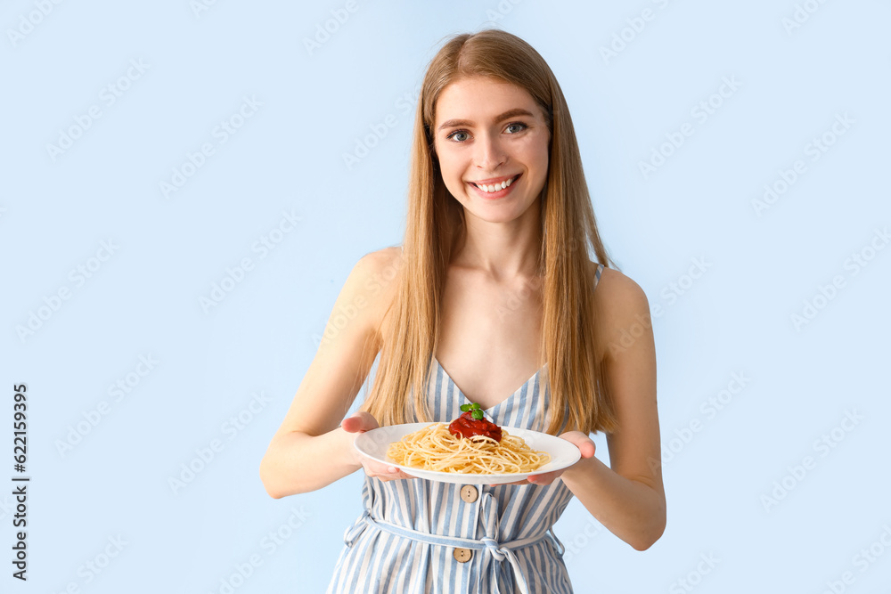 Young woman with tasty pasta on blue background